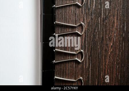 La catena di graffette metalliche nere spina il foglio di carta bianca sul tavolo di legno nell'ufficio domestico Foto Stock