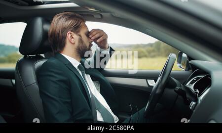 Uomo d'affari stanco seduto al sedile del conducente Foto Stock