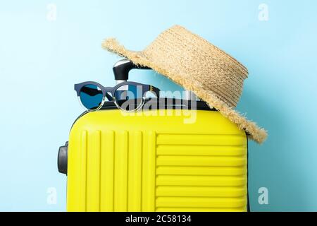 Borsa da viaggio con occhiali da sole e cappello su sfondo blu Foto Stock