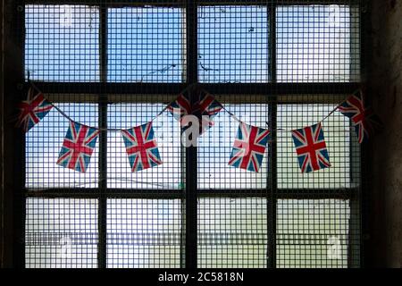 bandiere union jack su mungere attraverso la vecchia finestra alla griglia Foto Stock