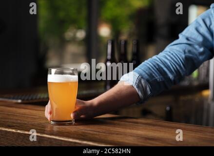 Oktoberfest in pub. Il barista tiene la birra lager in vetro all'interno del bar Foto Stock