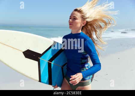 Donna con la tavola da surf di camminare sulla spiaggia Foto Stock