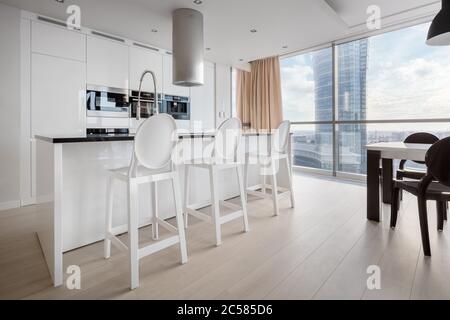 Elegante cucina interna in bianco e nero con grande parete finestra e tavolo da pranzo Foto Stock