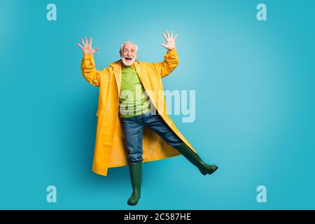 Vista a lunghezza intera del corpo del suo bel bell'uomo positivo con capelli grigi e un soprabito giallo che danzano divertendosi a tempo isolato Foto Stock