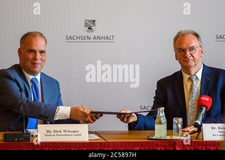 01 luglio 2020, Sassonia-Anhalt, Magdeburgo: Dirk Wössner (l), membro del consiglio di amministrazione di Deutsche Telekom AG e portavoce del consiglio di amministrazione di Telekom Deutschland, e Reiner Haseloff (r, CDU), ministro presidente dello Stato di Sassonia-Anhalt, scambiano il contratto relativo al «Patto digitale Sassonia-Anhalt». In questo accordo, si è deciso di portare avanti l'espansione Gigabit e l'espansione dei siti di comunicazione mobile e di implementare rapidamente procedure di approvazione e finanziamento. Foto: Klaus-Dietmar Gabbert/dpa-Zentralbild/dpa Foto Stock