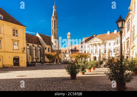 Sopron, Ungheria - Ottobre 2018: Statua della Trinità e Chiesa di Goat nel centro storico di Sopron, Ungheria Foto Stock