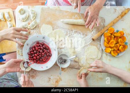 Preparazione di gnocchi dolci fatti in casa con frutta, cucina casalinga, mani di familiari, stile di vita reale. Vista dall'alto. Foto Stock