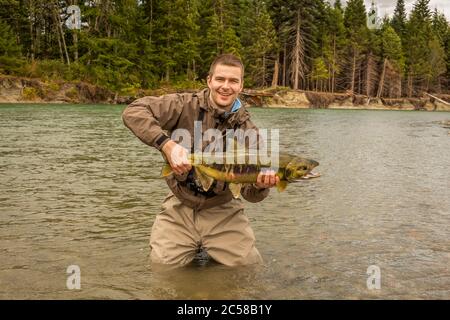 Un felice pescatore sportivo con orgoglio che tiene la sua cattura di un salmone Chum, sul fiume Kitimat, nella Columbia Britannica Foto Stock