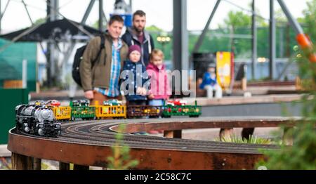 Bispingen, Germania. 01 Luglio 2020. I visitatori guardano un treno che passa sulla disposizione della ferrovia modello. Un totale di 500 treni devono rotolare attraverso vari mondi a tema su un percorso iniziale di 20 chilometri. La struttura, di 12,000 metri quadrati, si trova sotto la parte dello ski hall Snow Dome che sorge su palafitte. Secondo l'operatore, è il più grande modello di impianto ferroviario del mondo. Credit: Philippe Schulze/dpa/Alamy Live News Foto Stock