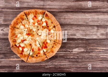 Tagliate a fette la pizza grande delisiosa a quattro formaggi, su sfondo di legno o tavolo con copyspace per il testo - volantino promozionale o poster concetto per pizze Foto Stock