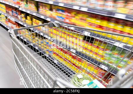 Carrello carrello di shopping che si muove in supermercato con movimento blur corsia con sfondo drogheria Foto Stock