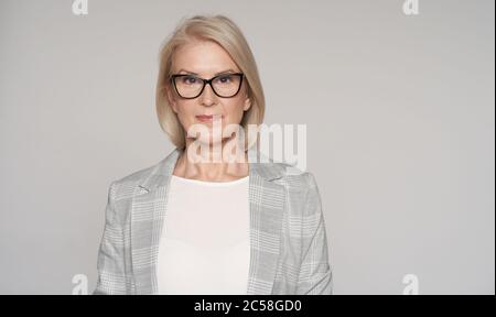 La donna bionda anziana indossa occhiali isolati su sfondo grigio Foto Stock