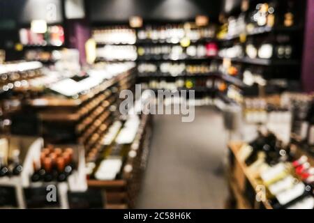 Sezione vino sfocato del rivenditore con bottiglie su scaffale display rack. Utilizzare come sfondo nella ricerca grafica Foto Stock