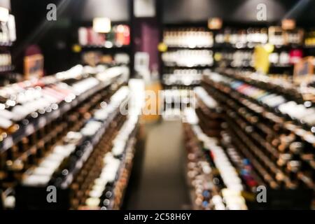 Sezione vino sfocato del rivenditore con bottiglie su scaffale display rack. Utilizzare come sfondo nella ricerca grafica Foto Stock