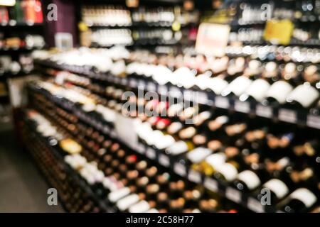 Sezione vino sfocato del rivenditore con bottiglie su scaffale display rack. Utilizzare come sfondo nella ricerca grafica Foto Stock