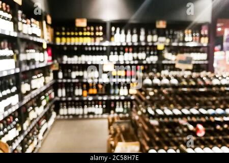 Sezione vino sfocato del rivenditore con bottiglie su scaffale display rack. Utilizzare come sfondo nella ricerca grafica Foto Stock