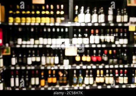 Sezione vino sfocato del rivenditore con bottiglie su scaffale display rack. Utilizzare come sfondo nella ricerca grafica Foto Stock