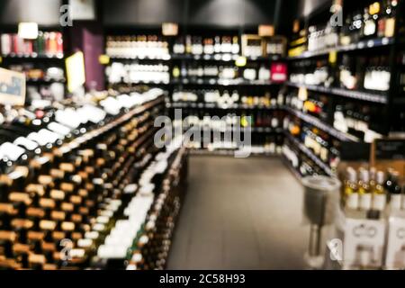 Sezione vino sfocato del rivenditore con bottiglie su scaffale display rack. Utilizzare come sfondo nella ricerca grafica Foto Stock