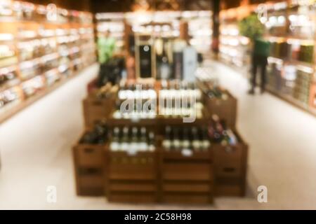 Sezione vino sfocato del rivenditore con bottiglie su scaffale display rack. Utilizzare come sfondo nella ricerca grafica Foto Stock