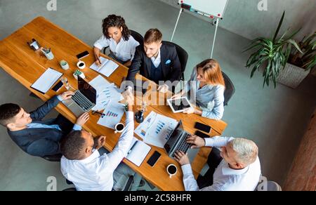 Due uomini d'affari che scuotono le mani durante la riunione in ufficio moderno, ad alta angolazione Foto Stock