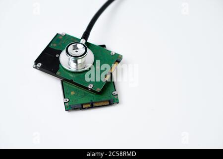 Un disco rigido con uno stetoscopio isolato su sfondo bianco. Ripristino e sicurezza dei dati Foto Stock