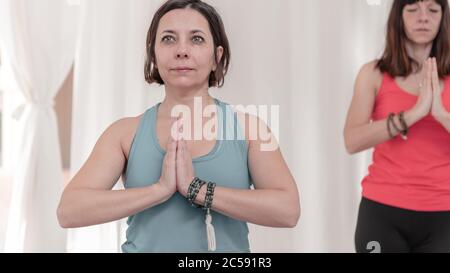 La donna in primo piano con le mani nel gesto di Namaste. Primo piano di ragazza meditating presso lo studio di yoga in gruppo. Come tenere le braccia in aria Foto Stock