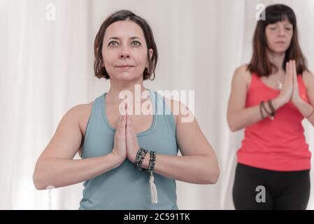 La donna in primo piano con le mani nel gesto di Namaste. Primo piano di ragazza meditating presso lo studio di yoga in gruppo. Come tenere le braccia in aria Foto Stock