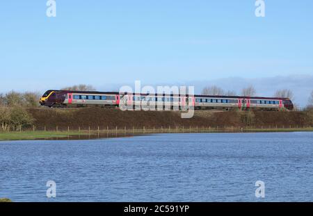 Treno passeggeri Voyager diesel-elettrico di classe 220, che passa per terra allagata a Staffordshire, Inghilterra, Regno Unito. Foto Stock