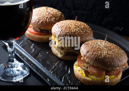 primo piano, bicchieri da birra con birra artigianale scura e chiara con schiuma, sullo sfondo di hamburger, con una varietà di ingredienti, tra cui lo shyomga Foto Stock