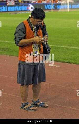 Split, Croazia - 17 agosto 2005: Fotogiornalista asiatico con accreditamento e una piccola macchina fotografica durante la partita di calcio amichevole Croazia - Brasile Foto Stock