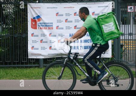 Mosca, Russia. 1 luglio 2020. Un uomo di consegna passa per la bandiera che si allira a partecipare al referendum sulle modifiche costituzionali a Mosca, Russia, 1 luglio 2020. La Russia ha indetto un referendum tra il 25 giugno e il 1 luglio su una serie di emendamenti costituzionali che, se approvati, consentiranno a Putin di partecipare alla corsa presidenziale del 2024. Credit: Evgeny Sinitsyn/Xinhua/Alamy Live News Foto Stock