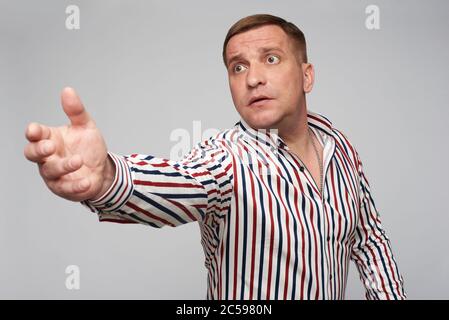L'uomo di mezza età chiede a qualcuno di tornare. Isolato su sfondo grigio Foto Stock