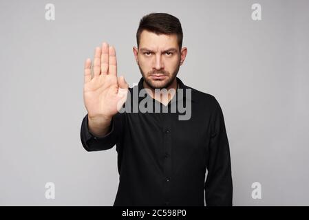 Ritratto di un uomo d'affari serio con la bearded che mostra il segno di stop su sfondo grigio Foto Stock