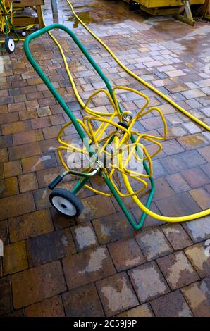 Una bobina per tubi da giardino con tubo resistente al kink giallo su bobine portatili e con ugelli a spruzzo pratica distribuzione in un centro di giardino scentrante Foto Stock