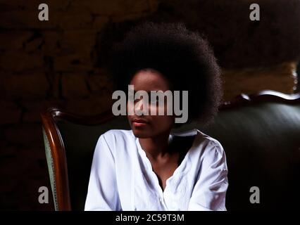 donna nera riposante su un divano verde in velluto Foto Stock