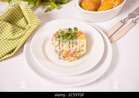 Insalata tradizionale russa Olivier con verdure e carne nel piatto bianco Foto Stock