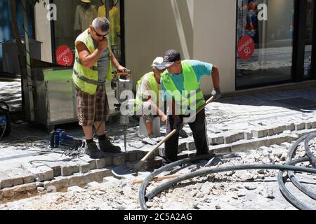 Grecia, Atene, giugno 28 2020 - operai edili che scavano e pavimentano piastrelle in una strada nel centro di Atene. Foto Stock