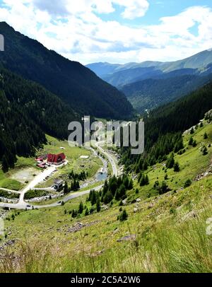 Fantastica valle di montagna. Vista su una bella strada di montagna con un asfalto perfetto all'alba in estate. Autostrada in montagna europea. Europa, Romania. Foto Stock