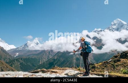 Giovane escursionista zaino in spalla con bastoni da trekking godendo la montagna di picco ama Dablam 6814m durante la camminata di acclimatazione ad alta quota. Base Cam Everest Foto Stock