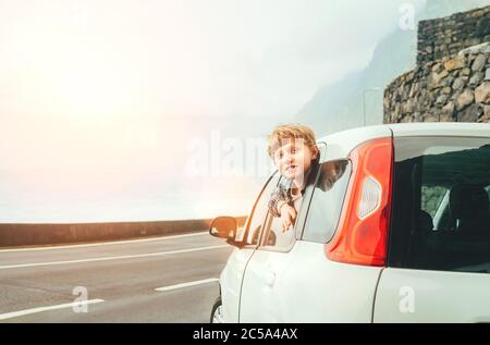 Ragazzo ragazzo biondo capelli guardare fuori dalla porta posteriore passangers di classe economica auto e smiling.Rental auto e viaggiare da auto concept immagine. Foto Stock