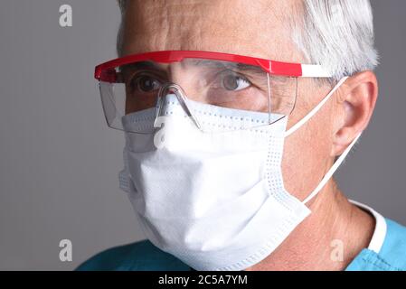 Ritratto di un medico che indossa scrub e dispositivi di protezione individuale, DPI. Solo per la testa di primo piano. Foto Stock