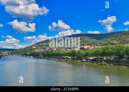 Il fiume Heidelberg neckar con vecchi edifici storici e la catena montuosa di Odenwald con il famoso castello in Germania durante l'estate Foto Stock