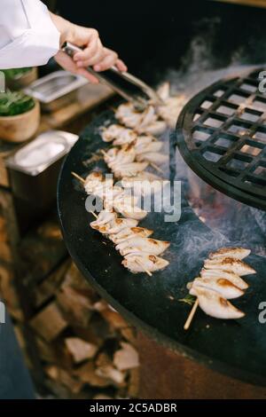 Lo chef prepara il calamaro su spiedini di legno. Foto Stock