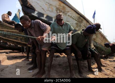 I pescatori rimorchiano una barca a riva al villaggio di pescatori di James Town ad Accra, Ghana. 4 settembre 2009. Foto Stock