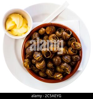 Immagine di gustose lumache cotte in ciotola, servite con pane e burro, nessuno. Isolato su sfondo bianco Foto Stock