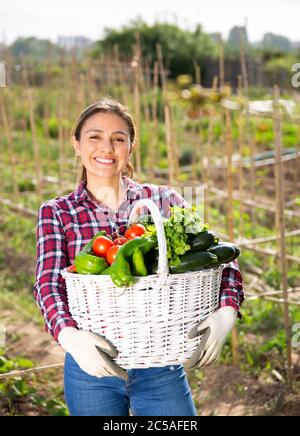 Felice contadino latino ragazza con cesto di verdure in giardino Foto Stock