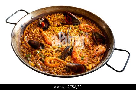 Paella spagnola con gamberi, calamari e cozze preparate in padella grande. Isolato su sfondo bianco Foto Stock