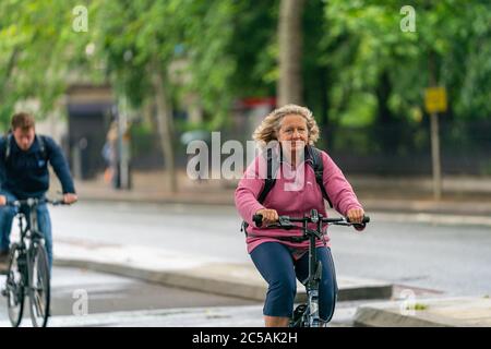 LONDRA, INGHILTERRA - 10 GIUGNO 2020: Sorriing amichevole vecchia donna in bicicletta pacifica in una giornata frizzante a Holborn, Londra durante la pandemia COVID-19 161 Foto Stock