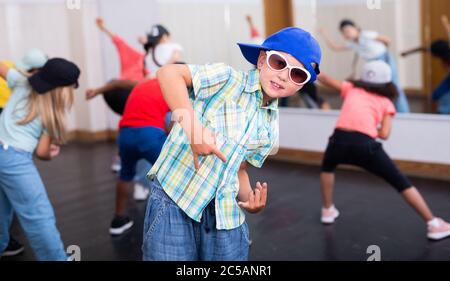 Ritratto di un ragazzo emozionale che fa movimenti hip hop durante la lezione di gruppo nel centro di danza Foto Stock