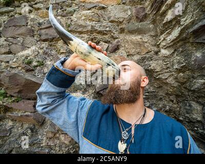 Ritratto di un giovane guerriero che beve da un corno vichingo, ambientazione all'aperto Foto Stock